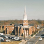 Clarendon Baptist Church's familiar 20th-century appearance, with its steeple rising above the surrounding development.